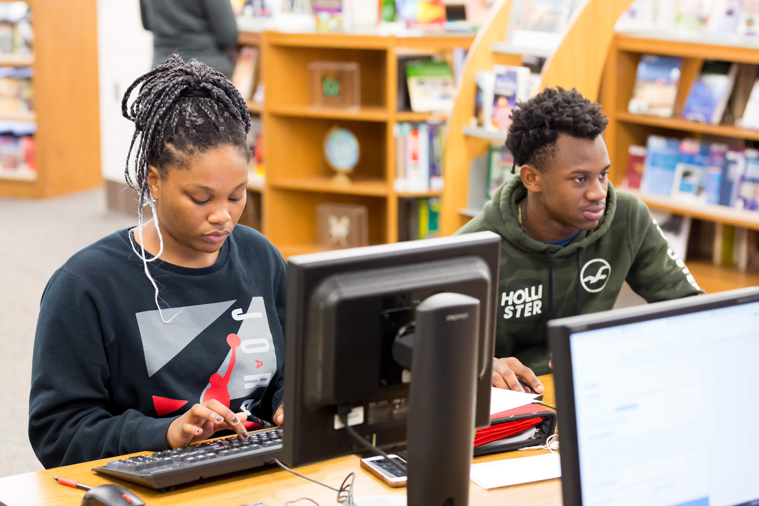 two students working at computers in a library